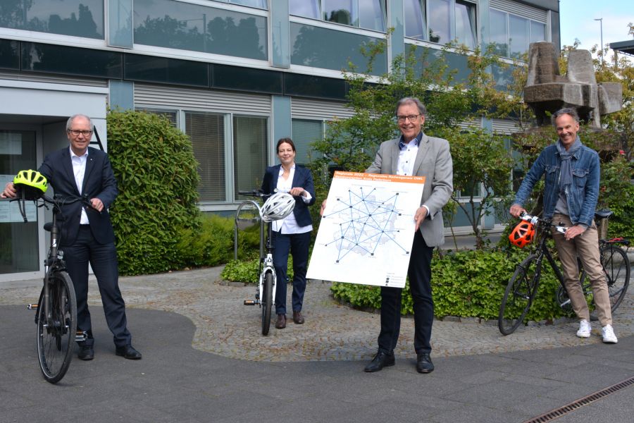 Hier auf dem Foto hält Christoph Schön eine Karte mit dem Radwegenetz in der Hand, Landrat Manfred Müller, Radverkehrsplanerin Linda Noack und Amtsleitung des Kreisstraßenbauamtes Michael Rüngeler stehen neben ihren Fahrrädern.